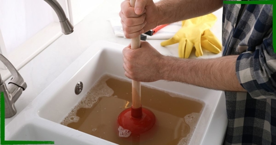 Man using a plunger to unclog a drain